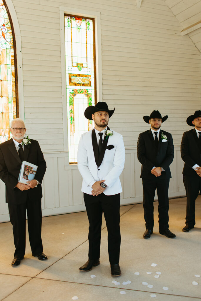 groom waits for bride as she walks down the aisle for their classy western wedding ceremony