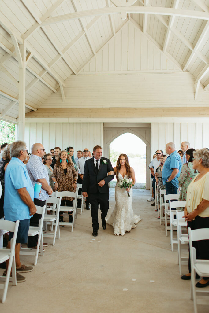 bride walks down the aisle for their classy western wedding ceremony