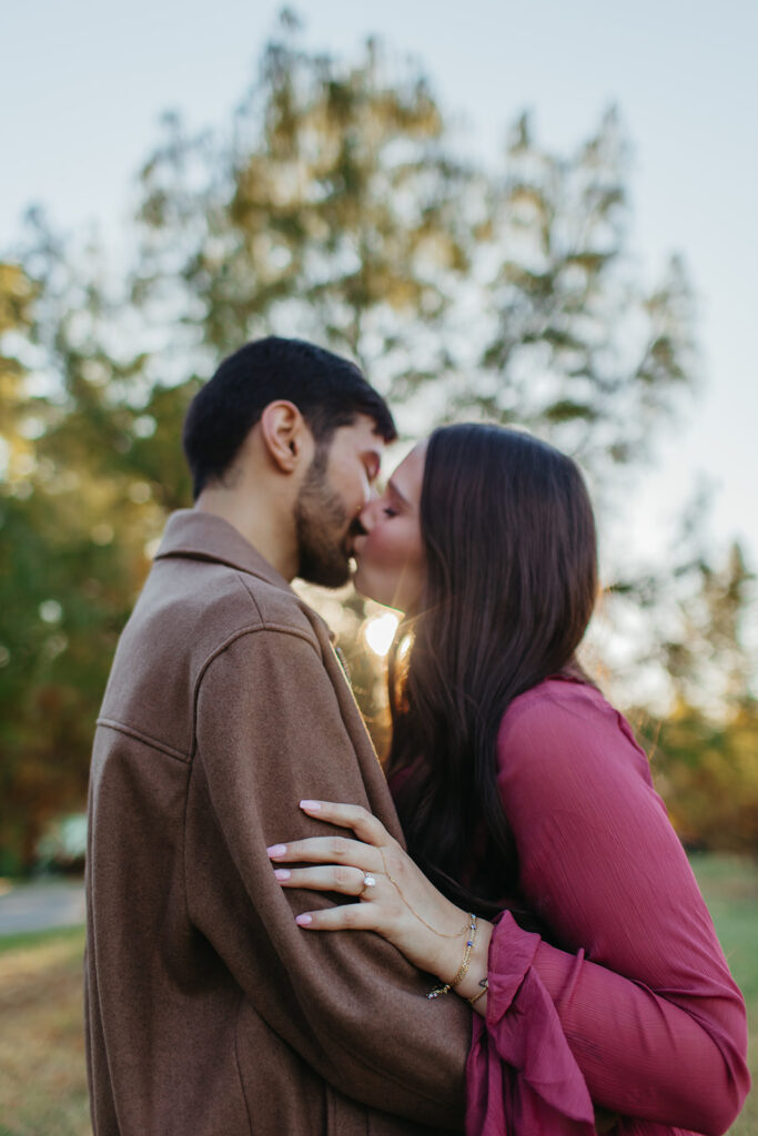 man and woman sharing a kiss at sunset for their engagement session