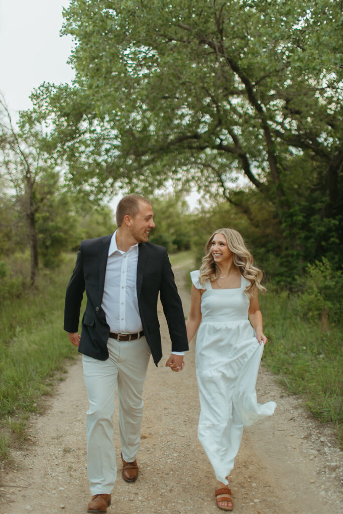 man and woman running down dirt path during their engagement session