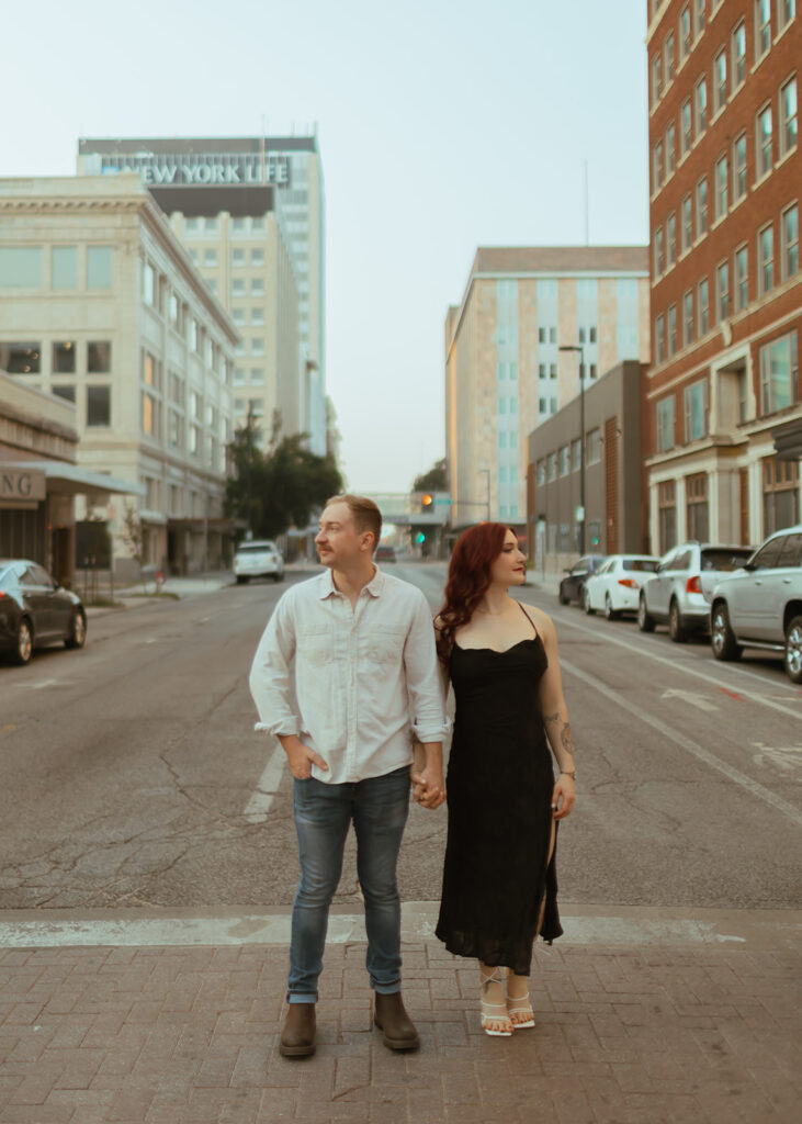 couple stands in the middle of the road holding hands for their editorial engagement shoot