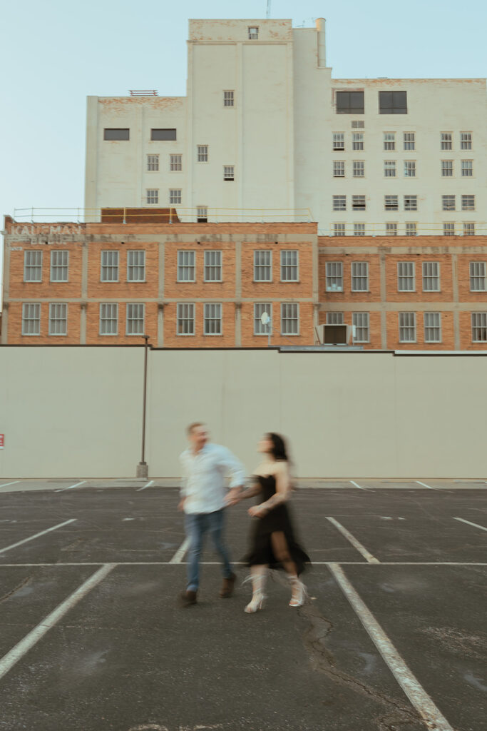 blurry shot of couple running on a parking garage rooftop for their editorial engagement shoot
