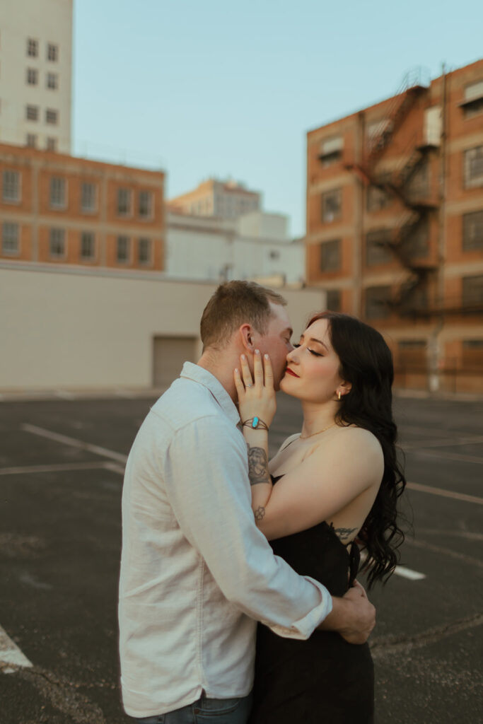 couple embraces on a parking garage rooftop for their editorial engagement shoot