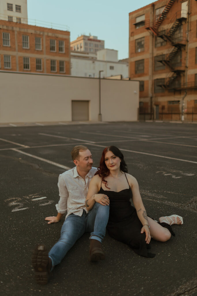 couple sitting on a parking garage rooftop for their editorial engagement shoot