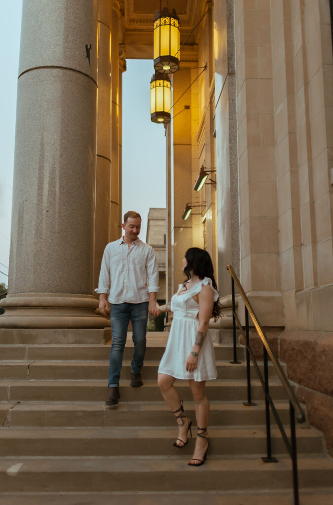 couple walks down steps of a stunning building for their editorial engagement shoot