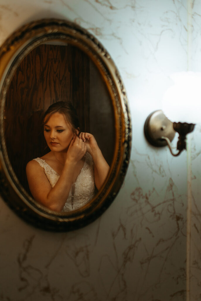 bride getting ready in a vintage mirror