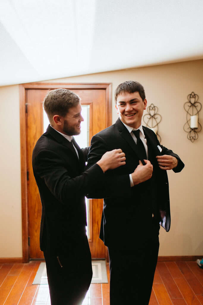 groomsmen helping groom with jacket