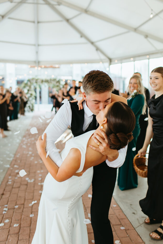 Bride and groom do a dip and kiss at the end of the aisle