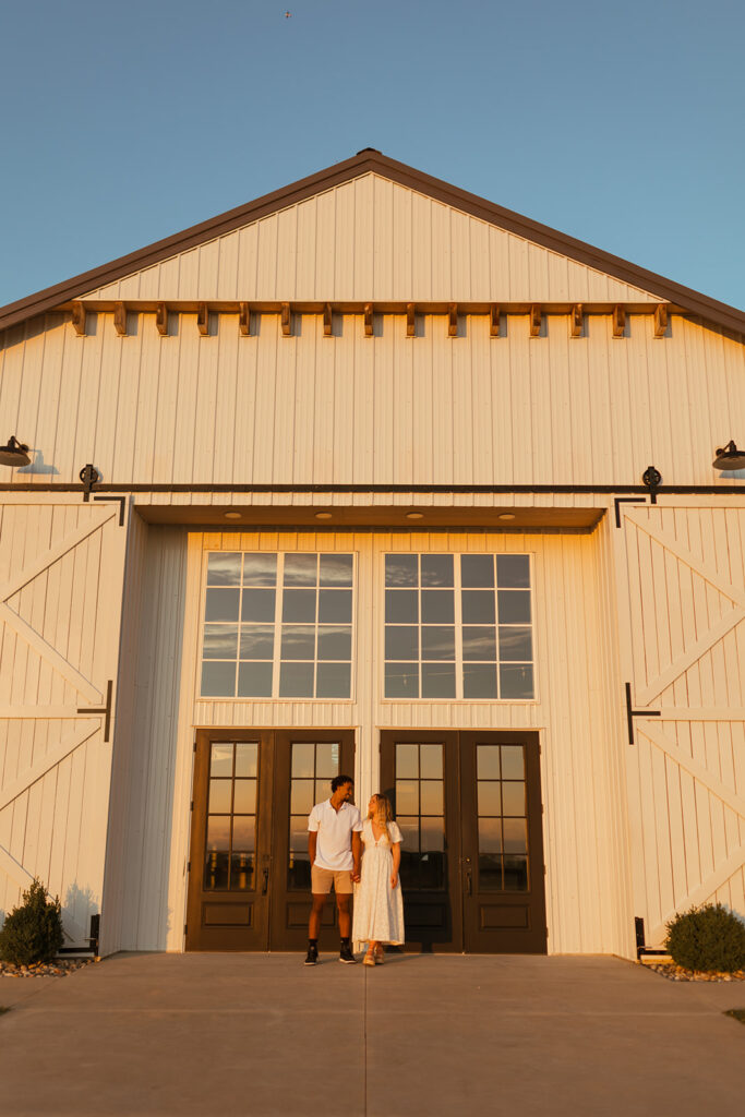 A couple standing in front of the barn at Grace Hill during their summer engagement session