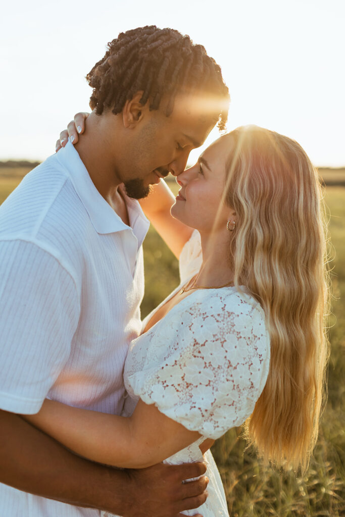 A couple touches noses as the sun peaks through during their engagement session in Kansas