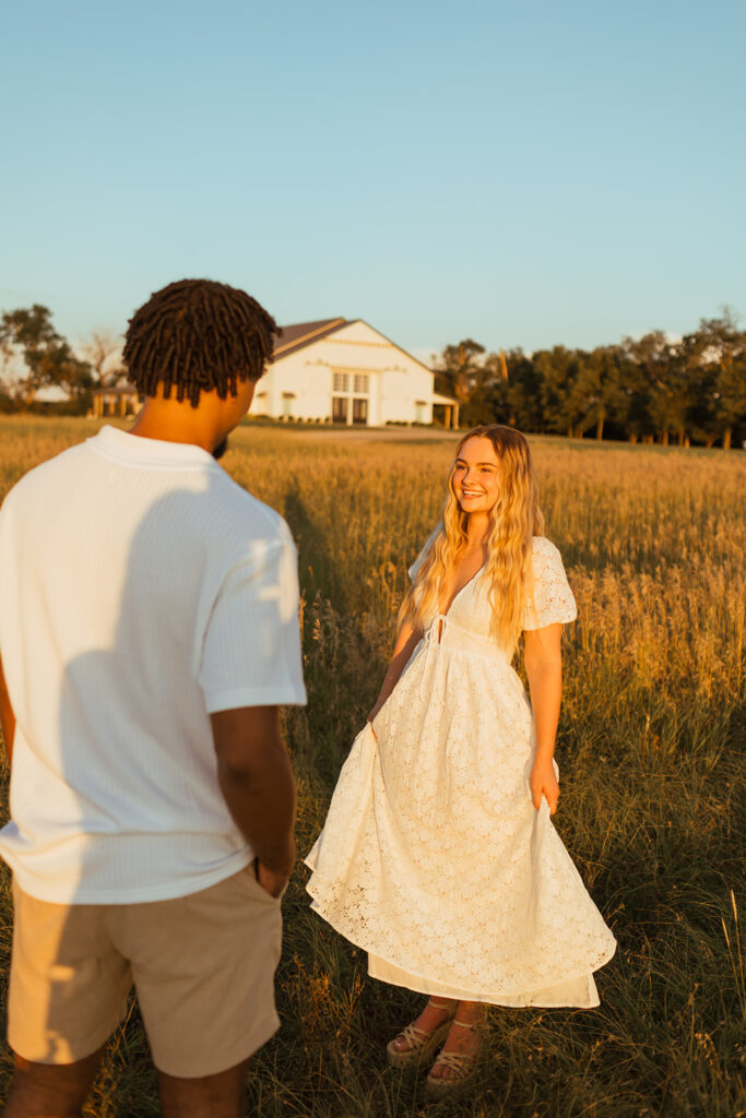 A couple doing their golden hour engagement photos with the barn at Grace Hill in the background