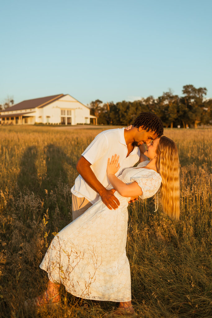 A couple doing their golden hour engagement photos with the barn at Grace Hill in the background