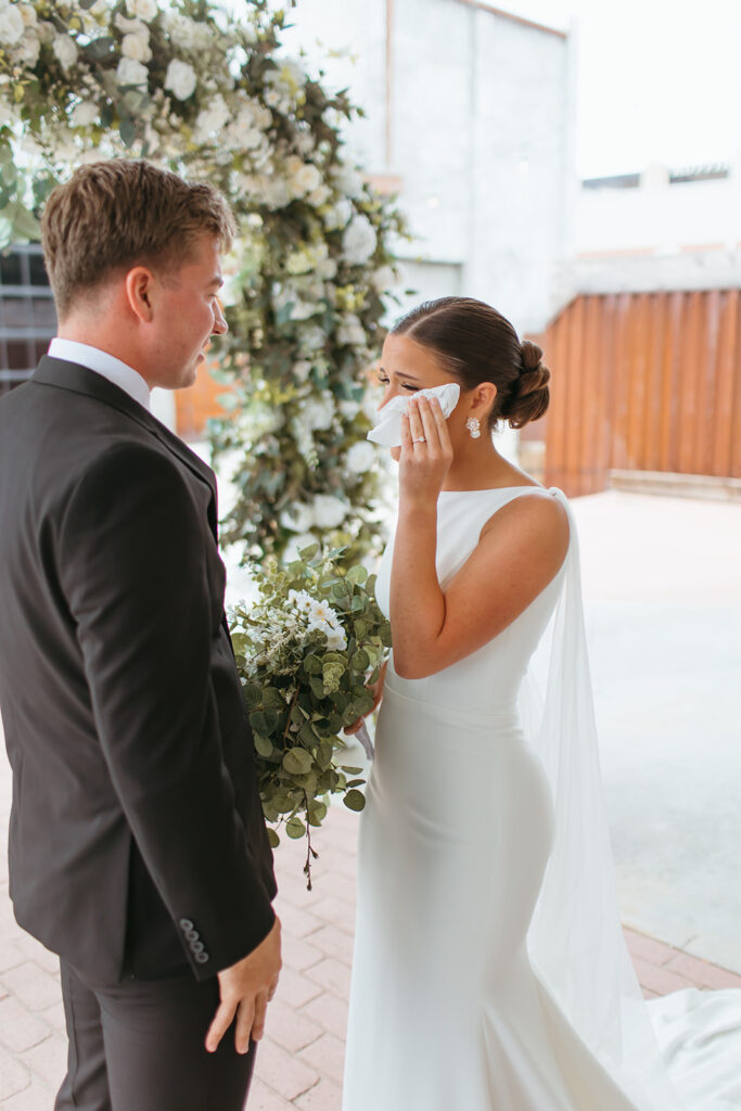 An emotional first look with the bride and groom on the patio at brick and mortar venue