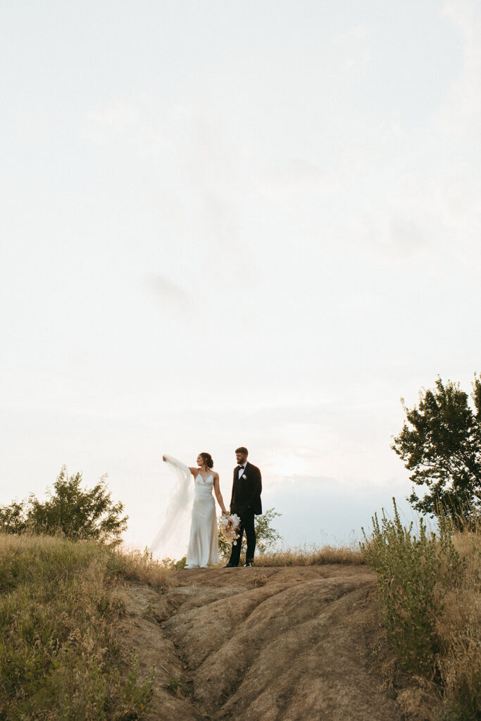 Bride and groom stand on a hill for some sunset bridal portraits