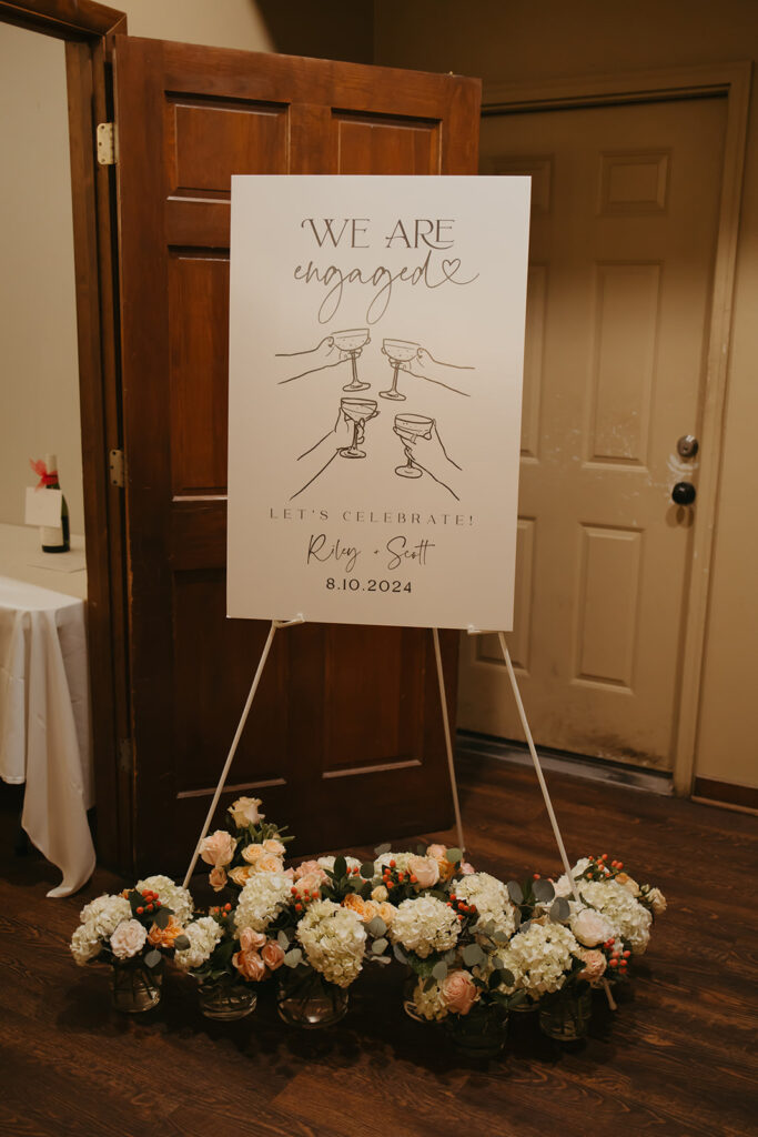 Engagement party sign with floral installation below