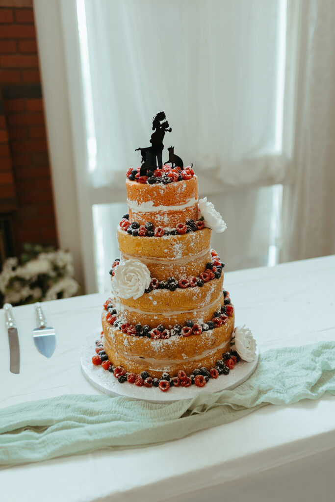 A naked wedding cake with blueberries and raspberries