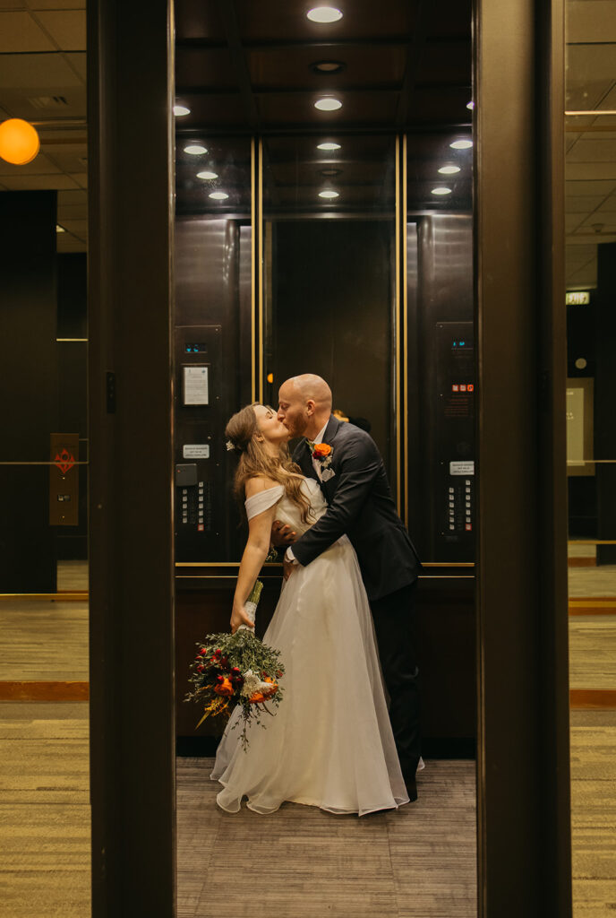 Bride and groom kissing in an elevator at Ninth Floor Club and Venue