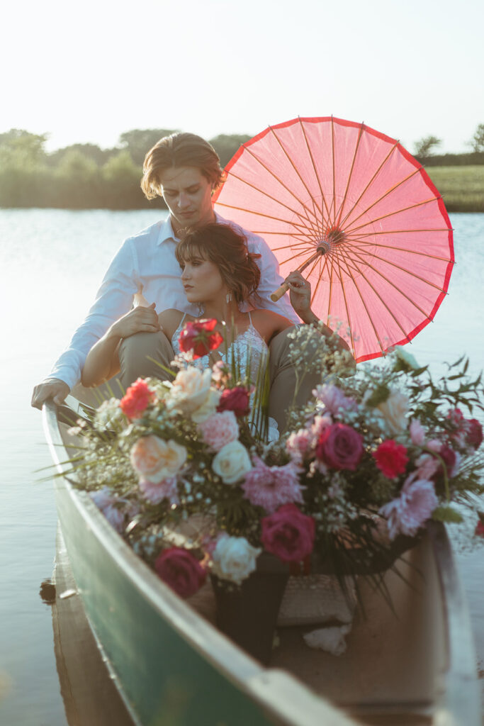 Bride and groom sit in a canoe with romantic florals in the pond at Atreeum greenhouse venue